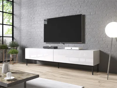 A modern living room scene featuring a TV on a white media console against a brick wall.