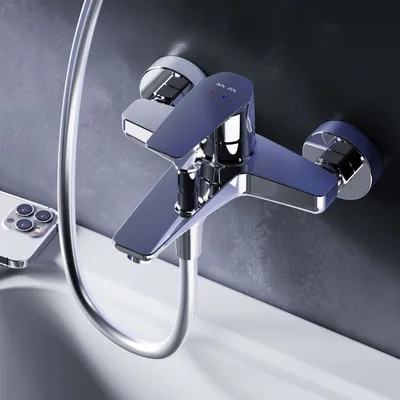 A close-up shot of a chrome and blue bathtub faucet mounted on a dark gray tiled wall, with a white bathtub visible in the foreground and a smartphone on the left.