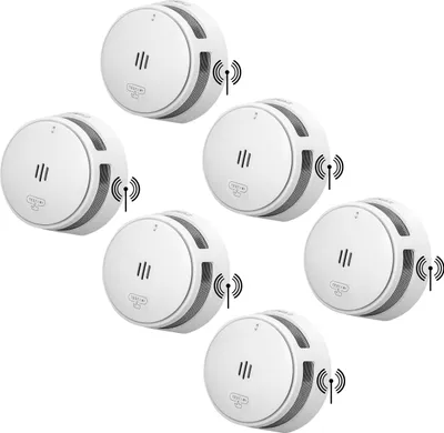 A group of six white smoke detectors arranged in a staggered pattern on a white background.