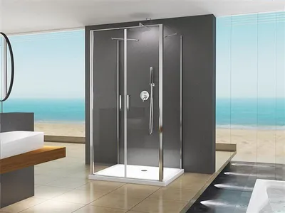 A modern bathroom with a shower cabin, sink, and bathtub, overlooking a beach and ocean.