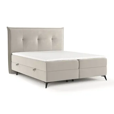 A studio shot of a beige boxspring bed with a tufted headboard and mattress.