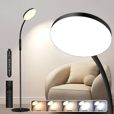 A black LED floor lamp with a large circular light head is shown next to a beige armchair. The lamp has a flexible arm and comes with a remote control. Several color temperature options are displayed at the bottom of the image.