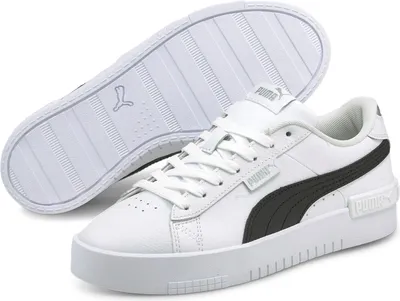 A pair of white Puma Jada sneakers with black accents, shown from a slightly elevated side angle. One shoe is upright, and the other is shown from the sole.