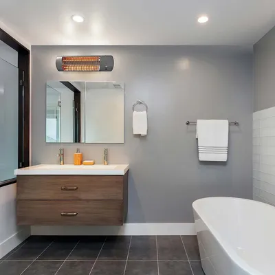 A modern bathroom with a vanity, bathtub, and a wall-mounted heater.