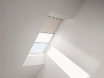 A skylight window with a partially lowered blind and a pleated shade.