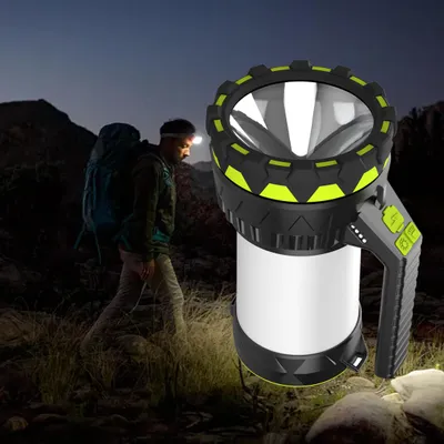 A person is hiking at night with a headlamp and carrying a large backpack. A powerful LED spotlight is in the foreground.