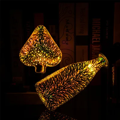 Two decorative LED light bulbs with a 3D firework effect, displayed against a dark background with books.