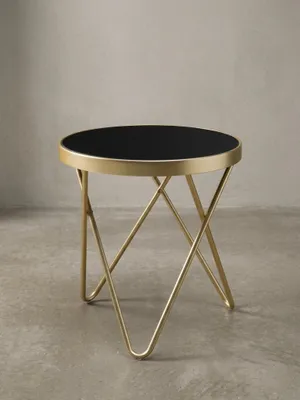 Runder Designer Beistelltisch PARMA frontal. Schwarzes Sicherheitsglas und ein matt-goldenes Gestell aus gekreuzten Streben vereinen sich zu einem 46 cm hohen, eleganten Möbelstück._#sku_SAFWL5.785#