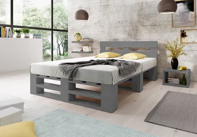A bedroom scene featuring a grey pallet bed with yellow pillows and a grey blanket.