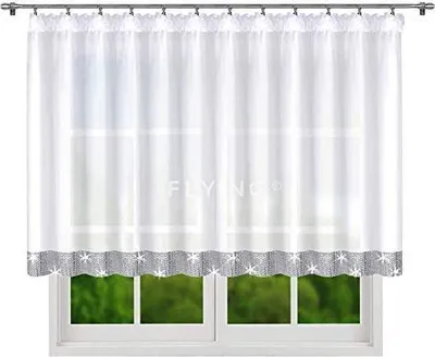 A white sheer curtain with a decorative gray border hangs in front of a window, revealing a blurred green outdoor scene.