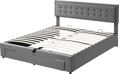 A grey upholstered bed frame with a tufted headboard and a slatted mattress support system is shown against a white background. The bed frame has built-in drawers visible at the foot of the bed.