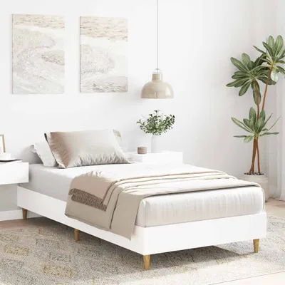 A white bed frame with bedding and a blanket is shown in a bedroom setting.