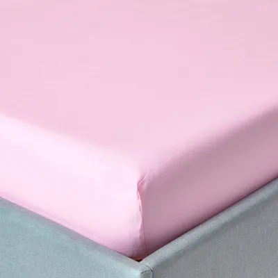 A close-up view of a pink fitted sheet on a bed.