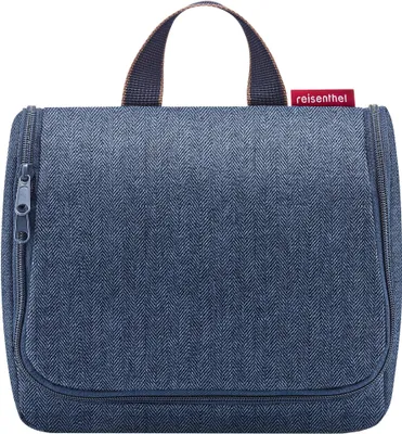 A blue toiletry bag with a herringbone pattern is shown against a white background.