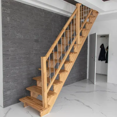 A wooden staircase with metal railings is shown in a modern interior with a gray stone wall and white marble flooring.
