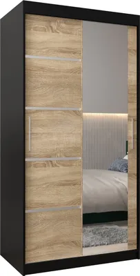 A modern wardrobe with sliding doors, one of which is mirrored, reflecting a bedroom interior.