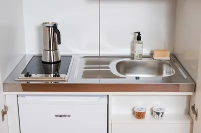 A compact kitchen unit with a stovetop, sink, and mini-fridge.
