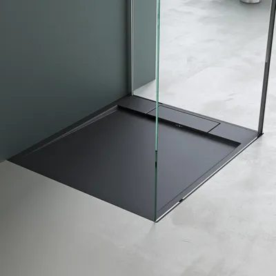 A modern, minimalist shower tray with glass enclosure and a dark gray wall.