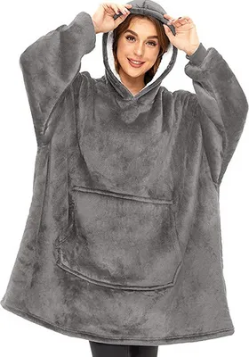 A woman wearing a grey oversized hoodie blanket.