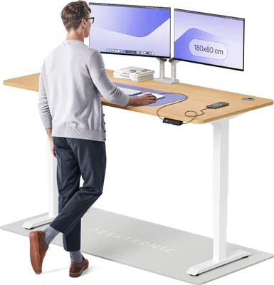 A man is standing at a height-adjustable desk, using a computer.