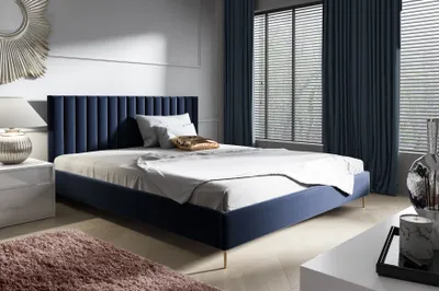 A bedroom scene with a blue upholstered bed and dark blue curtains.