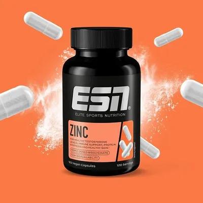 A bottle of ESN Zinc supplements is shown with several capsules floating around it against an orange background with powder effects.