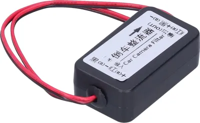 A black car camera filter with red and black wires attached, lying on a white background.