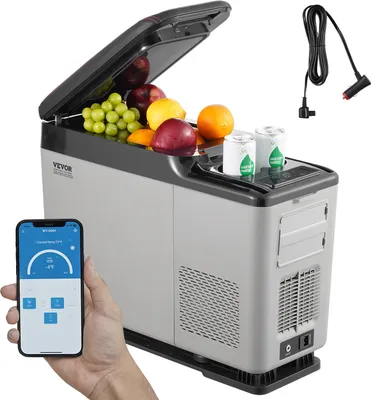 A VEVOR portable car refrigerator filled with fruit and cans, with a smartphone displaying its control interface in the foreground and a power cord in the background.