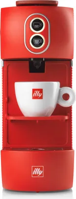 A red Illy capsule coffee machine with a white Illy branded cup on a shelf.