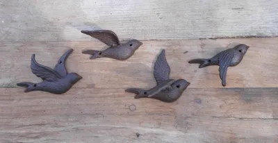 Four cast iron bird figures are arranged on a wooden surface.