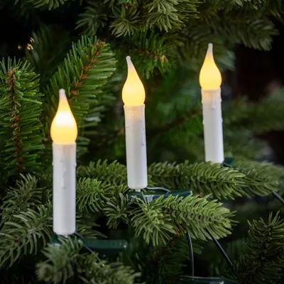 Three LED candle lights are attached to the branches of a Christmas tree.