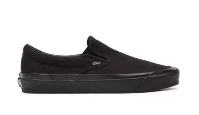 A black Vans slip-on shoe is shown from the side against a white background.