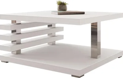 A white coffee table with a modern design, featuring a chrome leg and a shelf with horizontal slats.