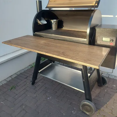 A wooden shelf attached to a black grill.