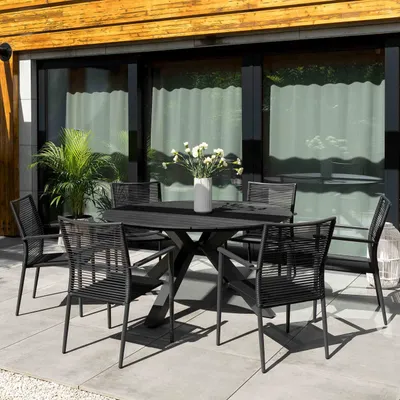 An outdoor dining set on a patio, with a modern house in the background.