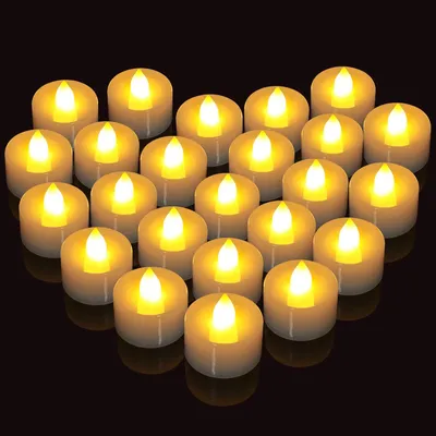 A collection of LED tea lights arranged in a heart shape against a black background.