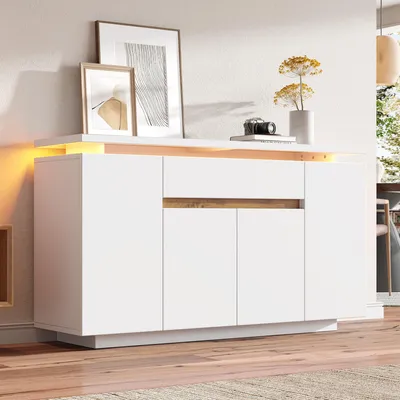 A white sideboard with wood accents and LED lighting, decorated with framed pictures and a vase of flowers.