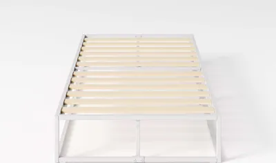 Weißes Metallbett ohne Matratze – stabile Holzlatten sichtbar.