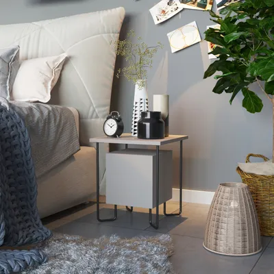 A bedroom scene with a nightstand next to a bed, decorated with various items.