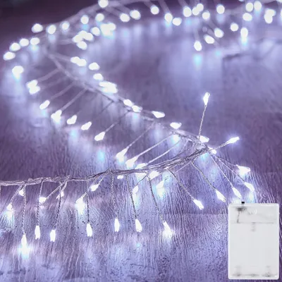 A string of white LED lights with a copper wire base is laid out on a wooden surface.