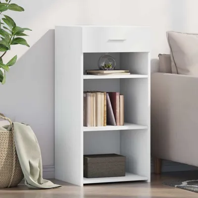 A white sideboard with shelves and a drawer, placed against a white wall next to a sofa.