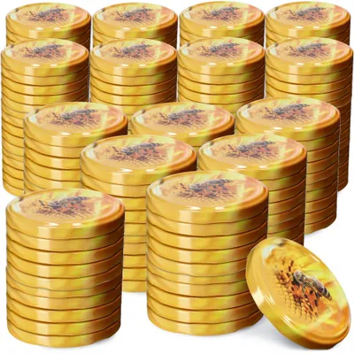 Stacks of metal lids with a bee and flower design, with one lid in the foreground showing the design clearly.