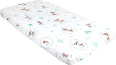 A white crib sheet with a pattern of deer and leaves.