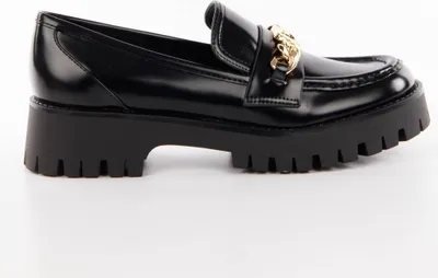 A black loafer with a gold chain detail and a thick black sole, shown from the side against a white background.