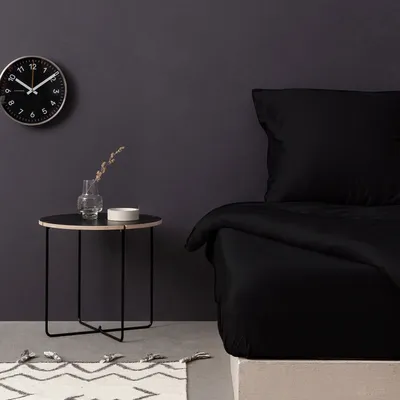 A bedroom scene with a bed, side table, and clock.