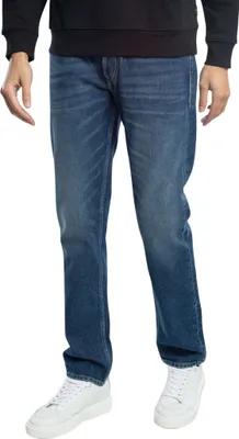 A person wearing blue jeans and white sneakers, shown from the waist down.
