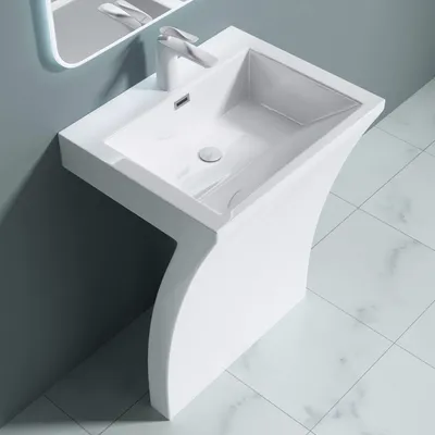 A modern white pedestal sink with a curved base, set against a gray wall and tiled floor.