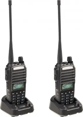 Two black walkie-talkies are shown in their charging docks against a white background.