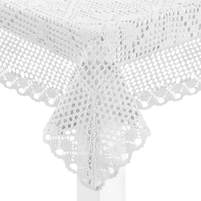 A close-up view of a white crocheted tablecloth draped over a corner of a table.