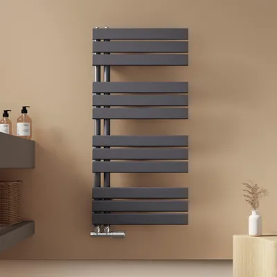 A modern anthracite radiator mounted on a light brown wall in a bathroom setting.